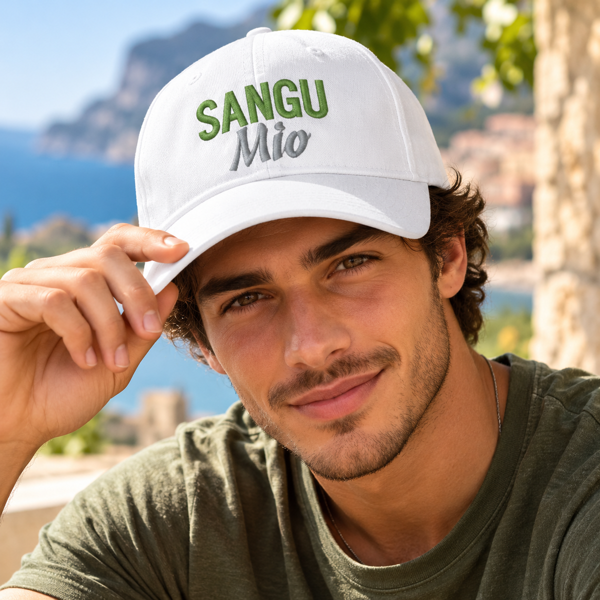 Handsome young Italian man wearing a white Sangu Mio embroidered baseball cap with green and silver lettering. Sicilian heritage hat celebrating family pride.