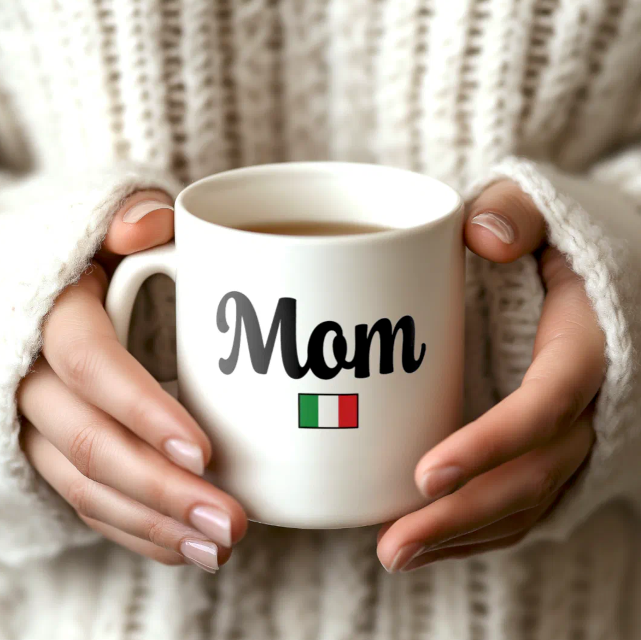 White mug with 'Mom' and Italian flag held by hands against a neutral background