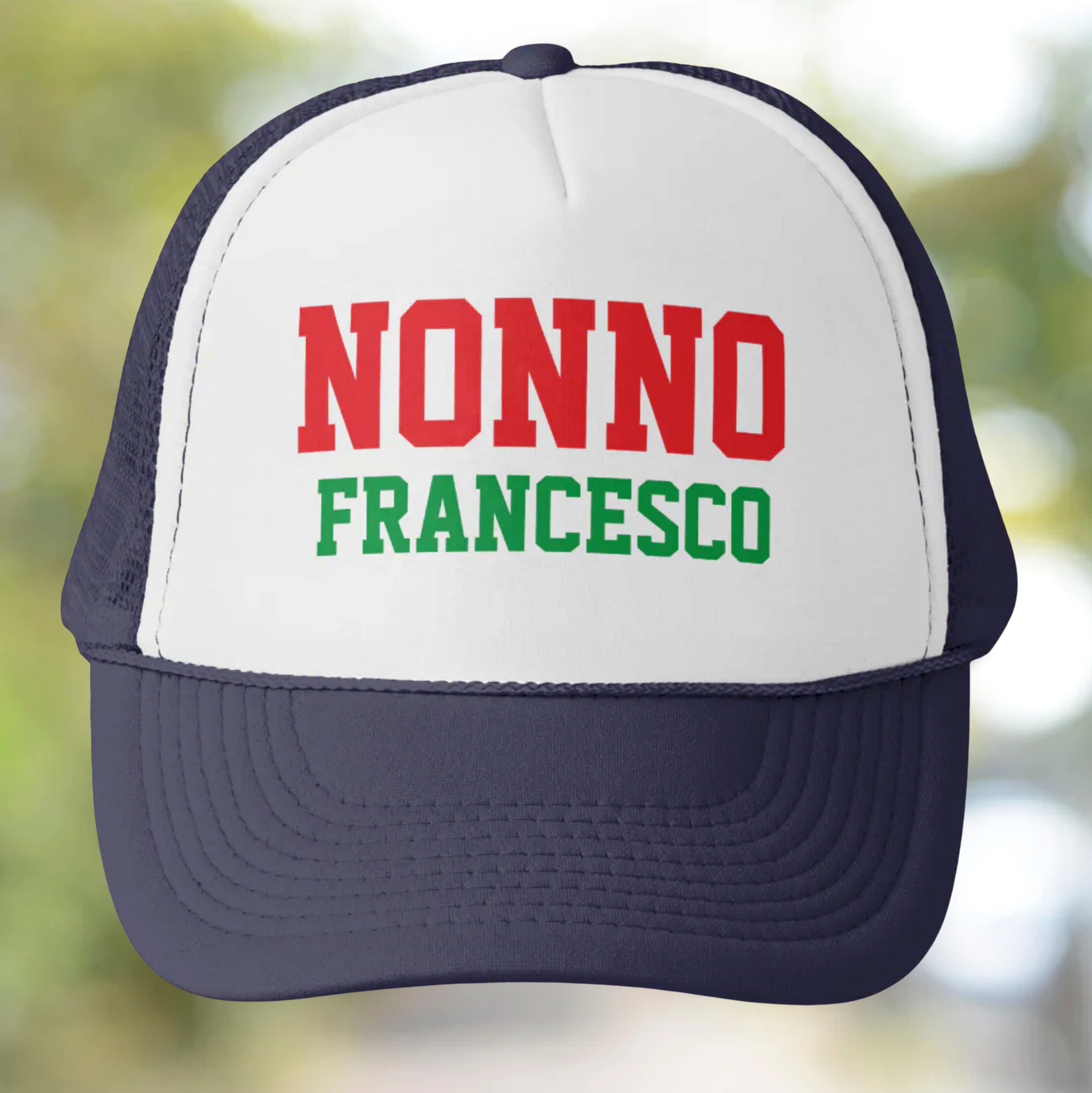 Trucker hat with 'NONNO FRANCESCO' personalized text on a blurred natural background