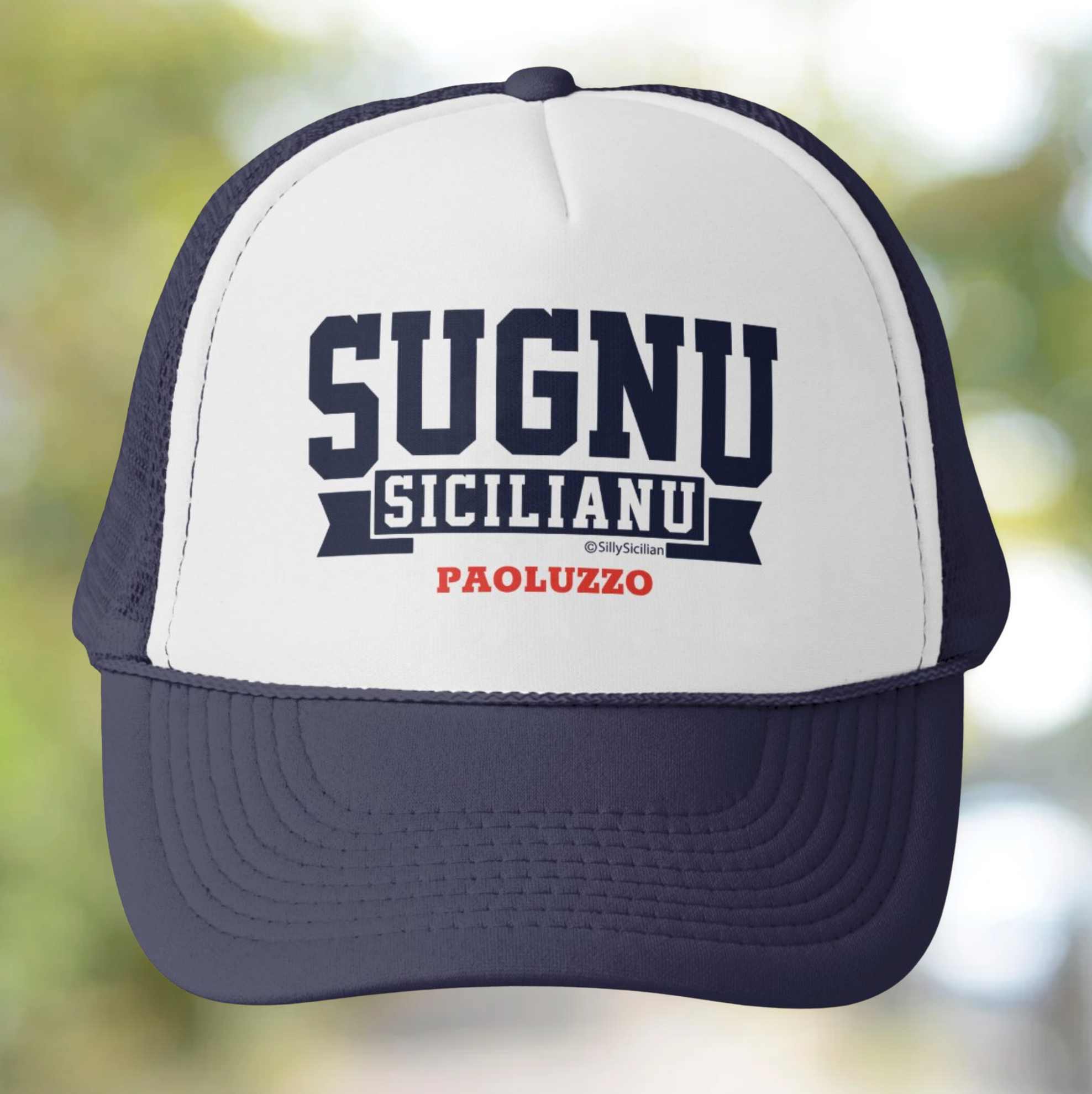 Trucker hat with 'SUGNU SICILIANU PAOLUZZO' personalized text on a blurred natural background