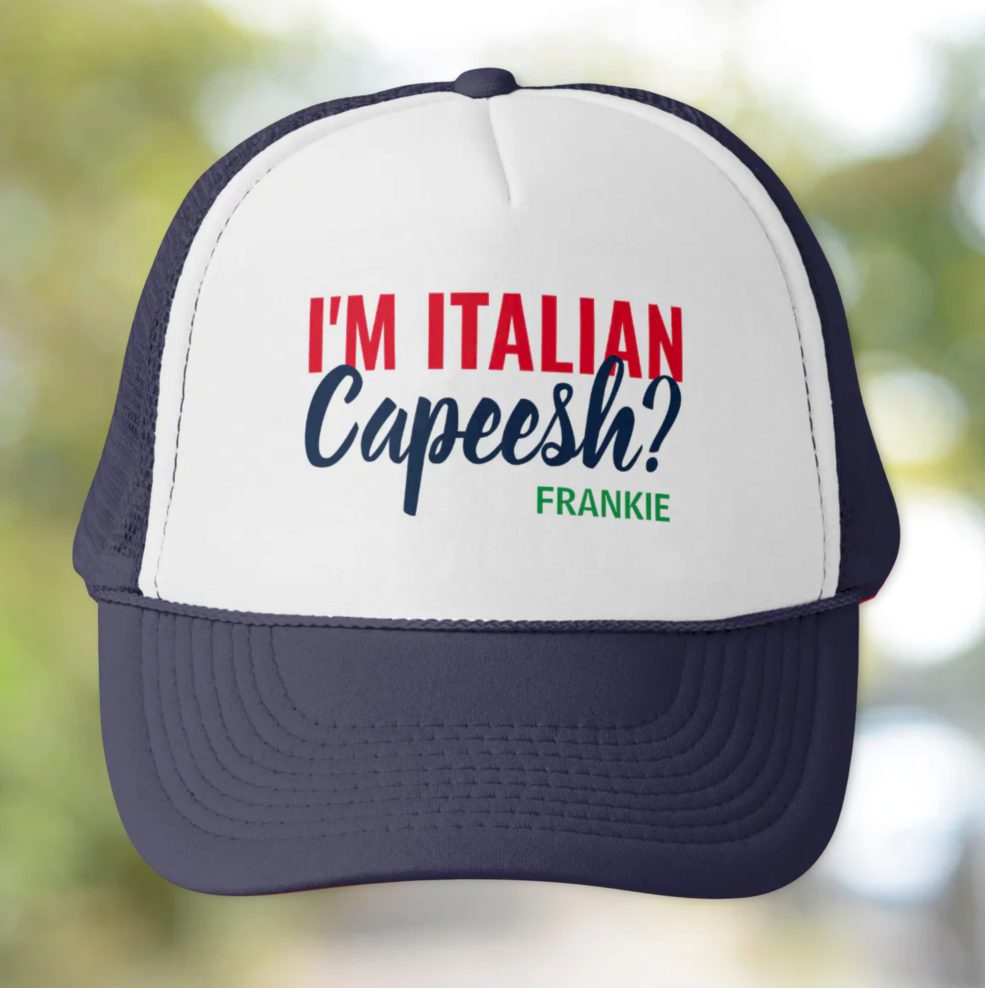 Trucker hat with text 'I'm Italian Capeesh? Frankie' personalized on a blurred natural background