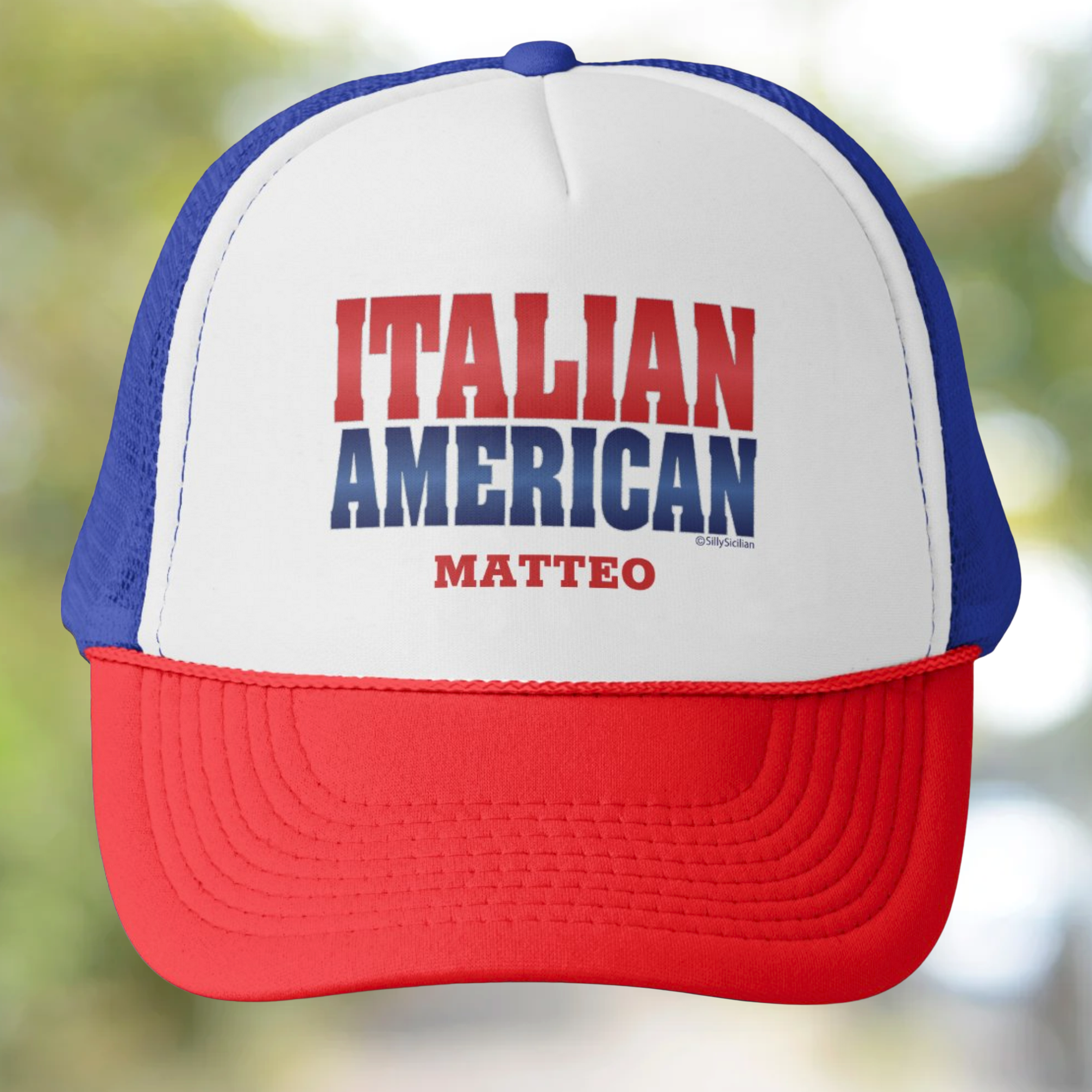 Trucker hat with 'ITALIAN AMERICAN MATTEO' personalized text on a blurred natural background