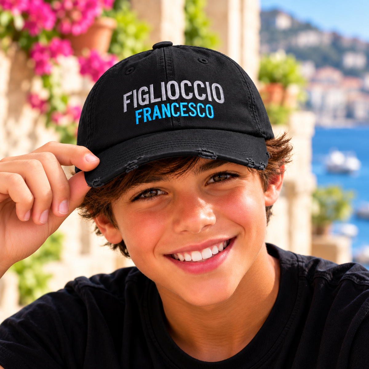 Smiling Italian boy wearing personalized black Figlioccio embroidered baseball cap with Francesco in blue lettering. Italian godson gift for baptism, christening or birthdays.