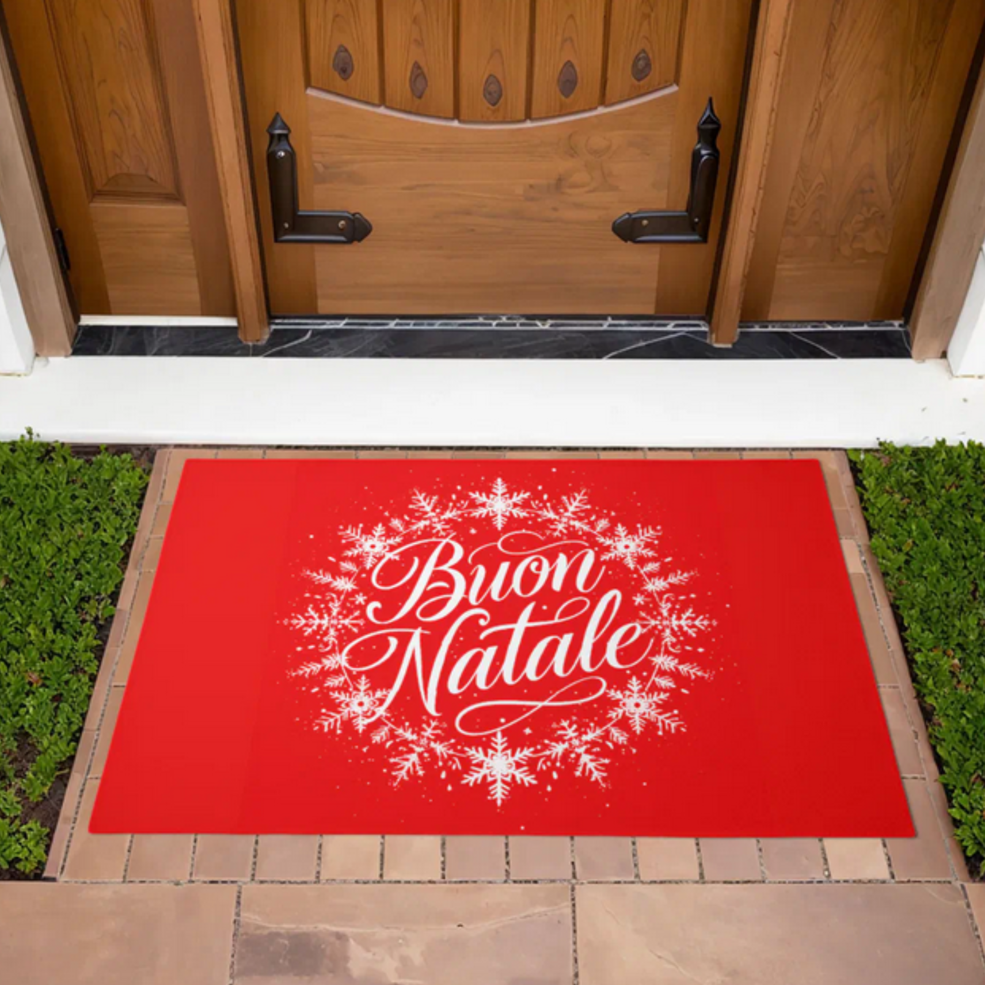 Red doormat with 'Buon Natale' text and snowflakes on a wooden door step.