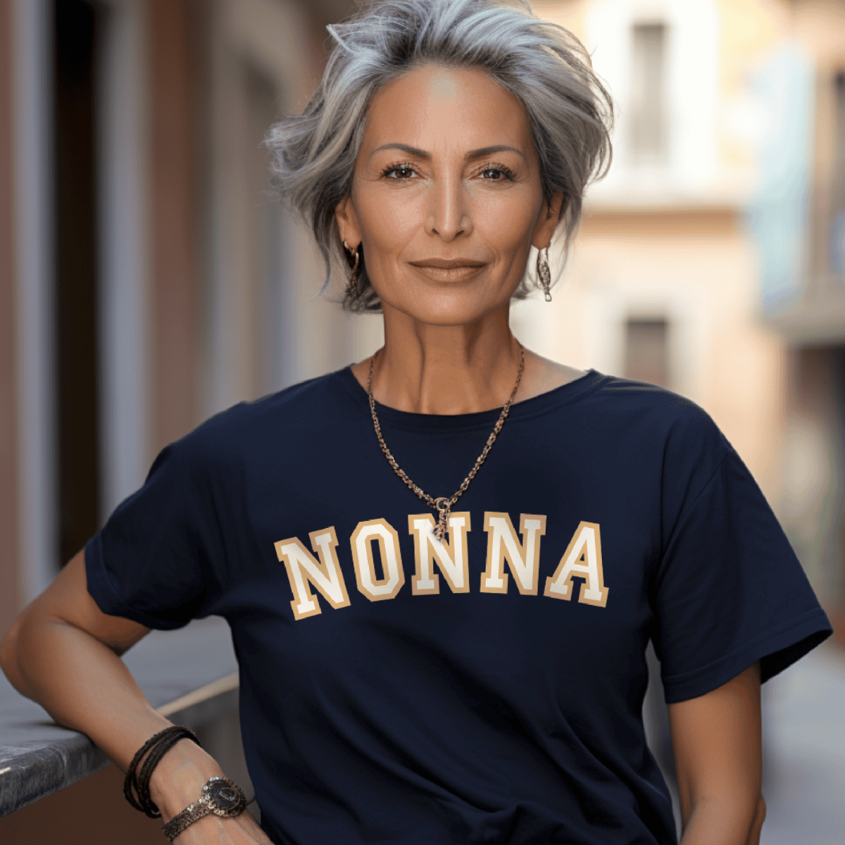 Bold arched “Nonna” athletic typography design with gold-look outline and cream lettering printed on a navy blue t-shirt, available in multiple color options. Sicilian and Italian heritage gift for grandmother.