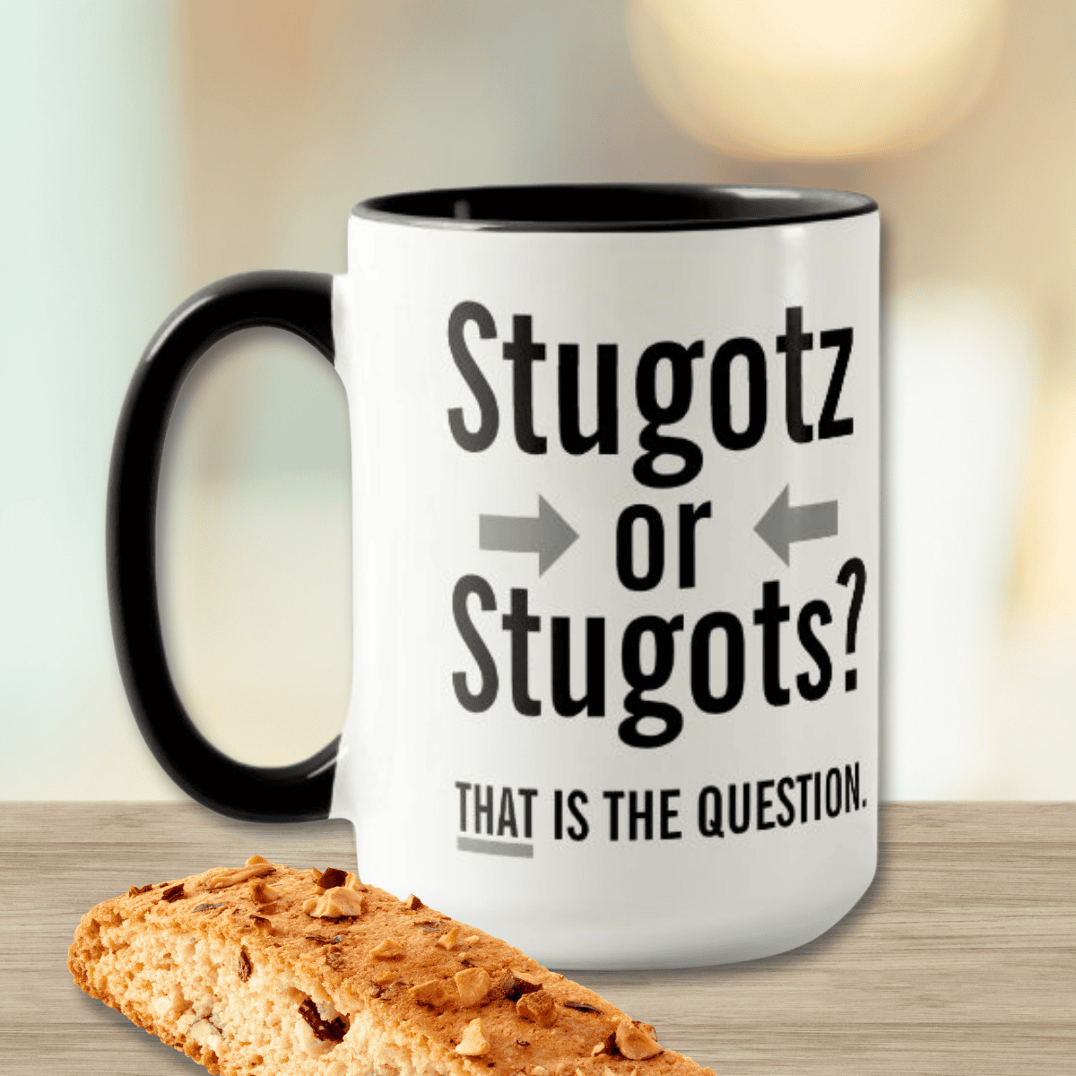 White mug with black handle featuring bold black text reading “Stugotz or Stugots — That is the question,” accented with subtle gray arrows, celebrating Sicilian and Italian heritage humor and classic Italian-American wordplay