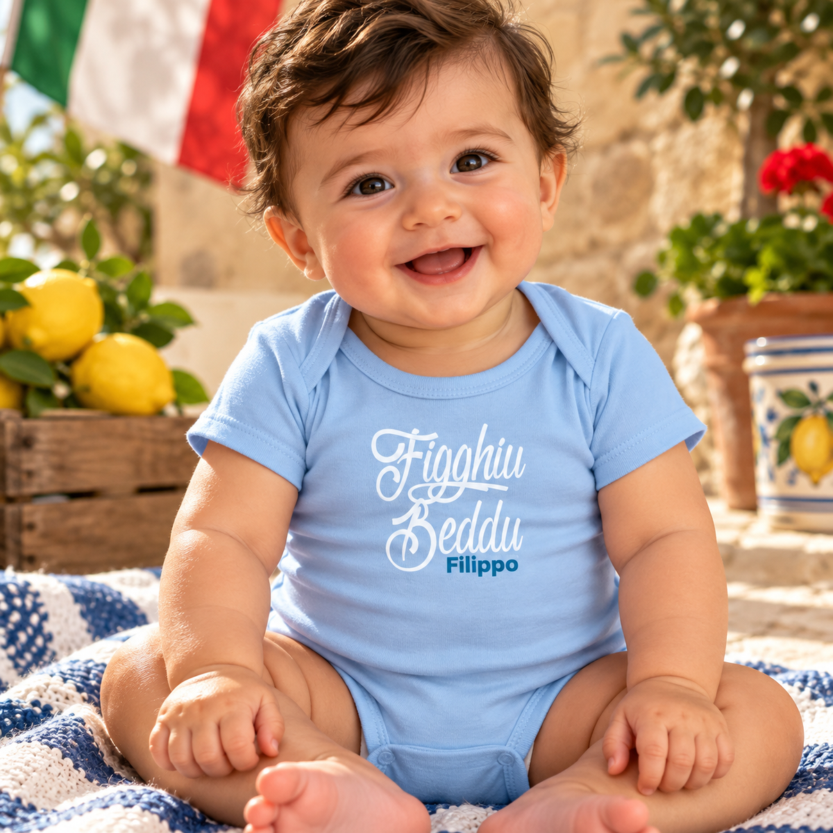 Smiling baby boy wearing a personalized blue “Figghiu Beddu” Sicilian bodysuit, meaning “Beautiful Son” or “Beautiful Boy,” with the name Filippo.