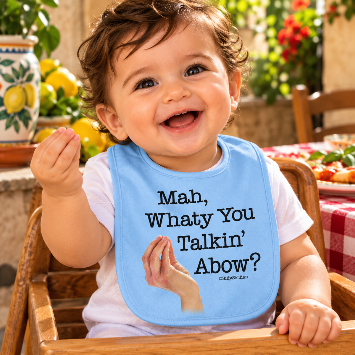 Adorable Italian baby boy wearing a blue “Mah, Whatty You Talkin’ Abow?” bib with classic Italian hand gestures, seated in a charming Italian kitchen.