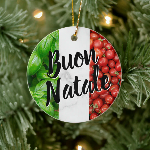 Decorative ornament with 'Buon Natale' text on a green, white, and red background, basil and tomatoes, hanging on a Christmas tree.