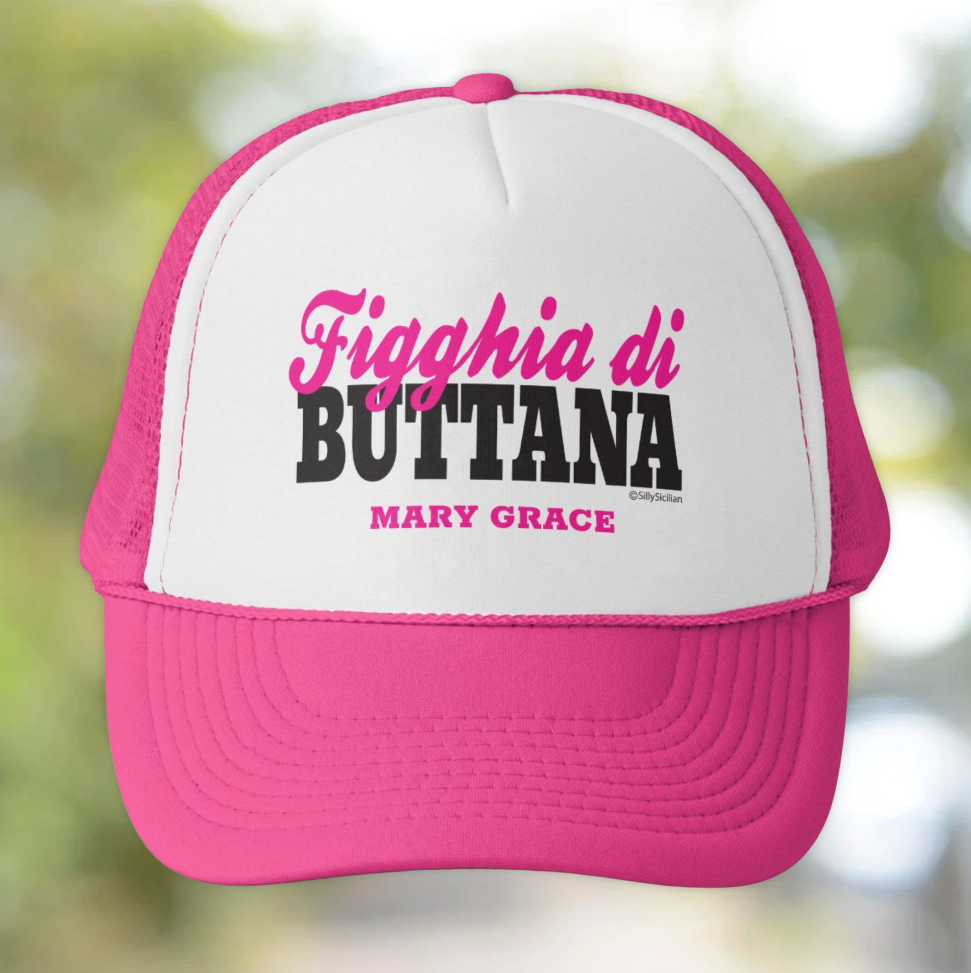 Pink and white cap with Figghia di Buttana personalized text on a blurred natural background