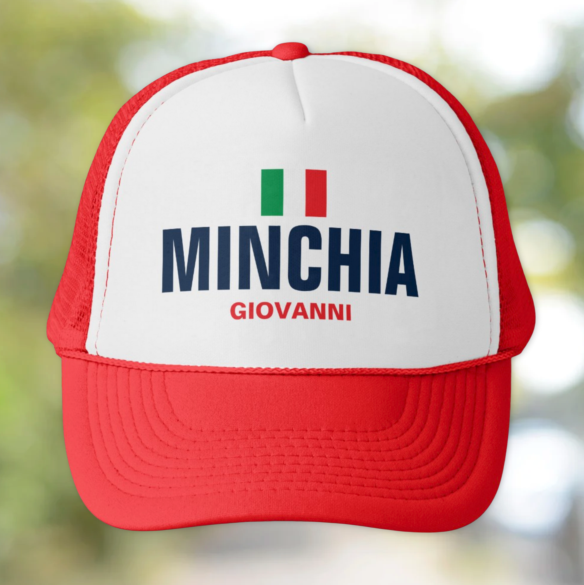 Red and white cap with 'MINCHIA GIOVANNI' personalized text and Italian flag on a blurred natural background