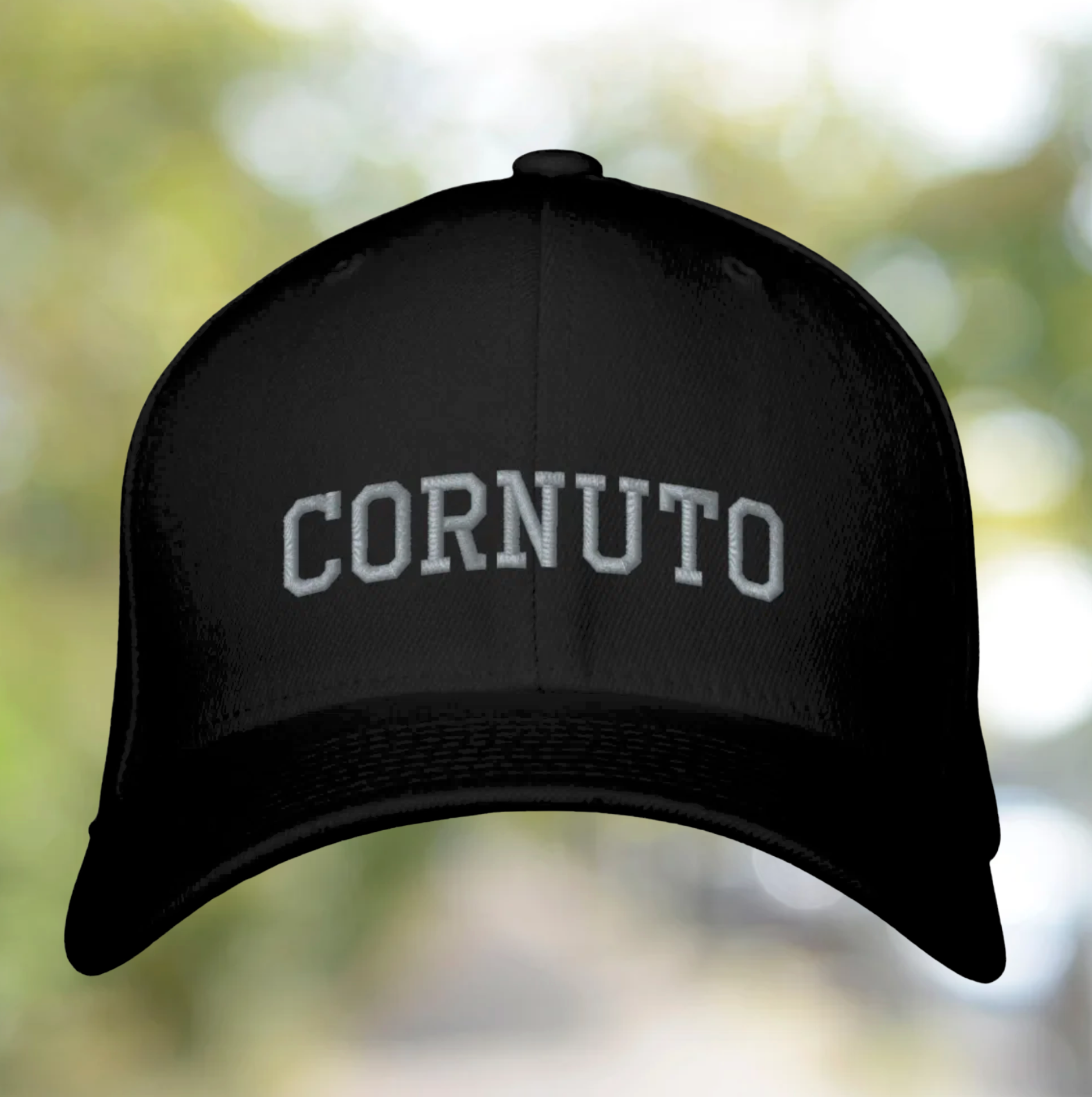Black cap with 'CORNUTO' text on a blurred natural background
