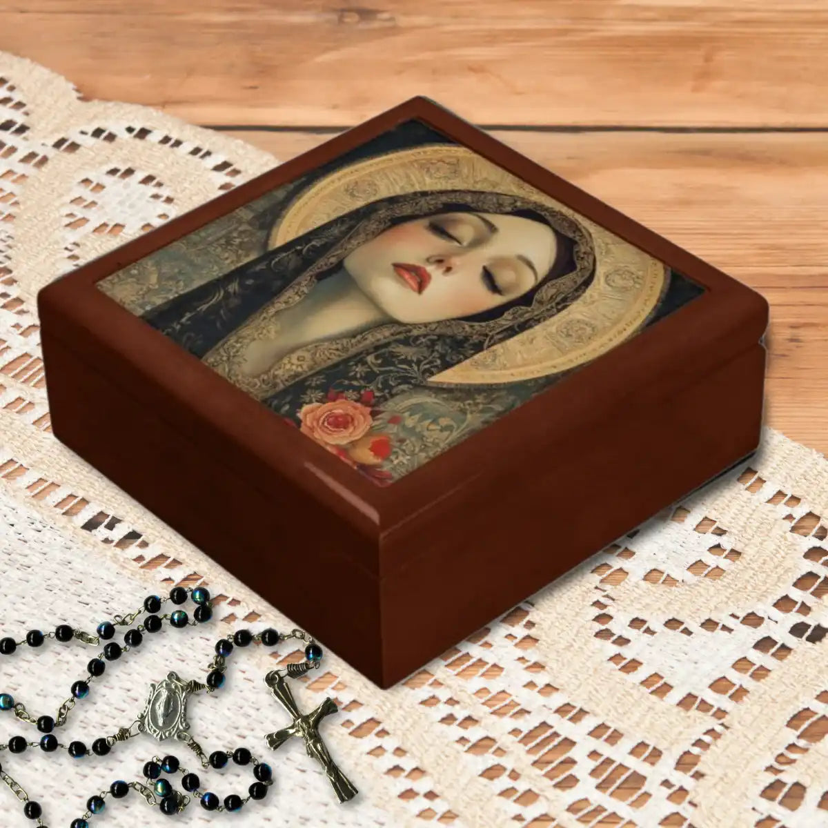 Wooden keepsake box with an image of a religious figure Mother Mary on a lace surface with a rosary.
