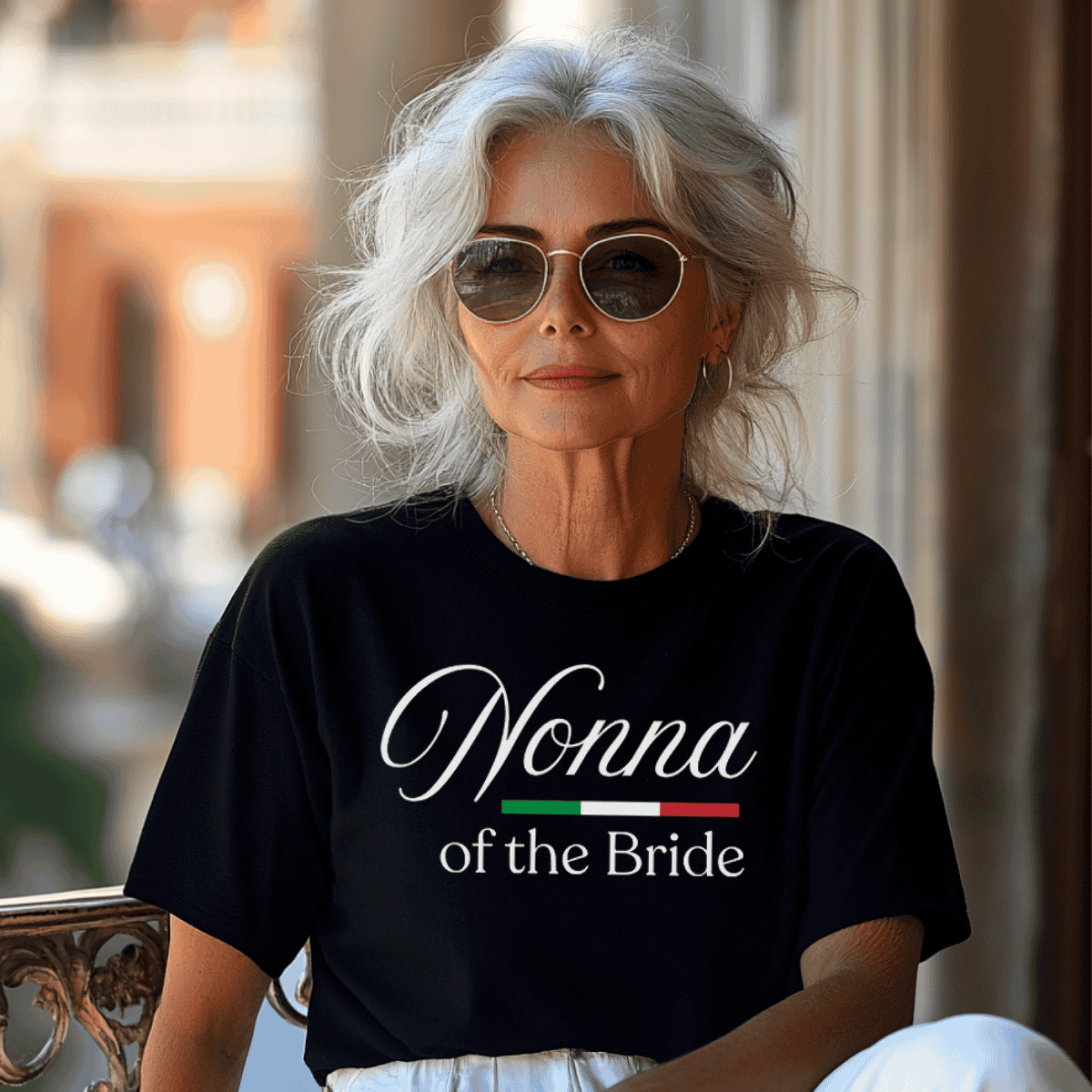 Woman wearing a black t-shirt with 'Nonna of the Bride' text and Italian flag design. From a matching bridal party t-shirt collection for the whole family.